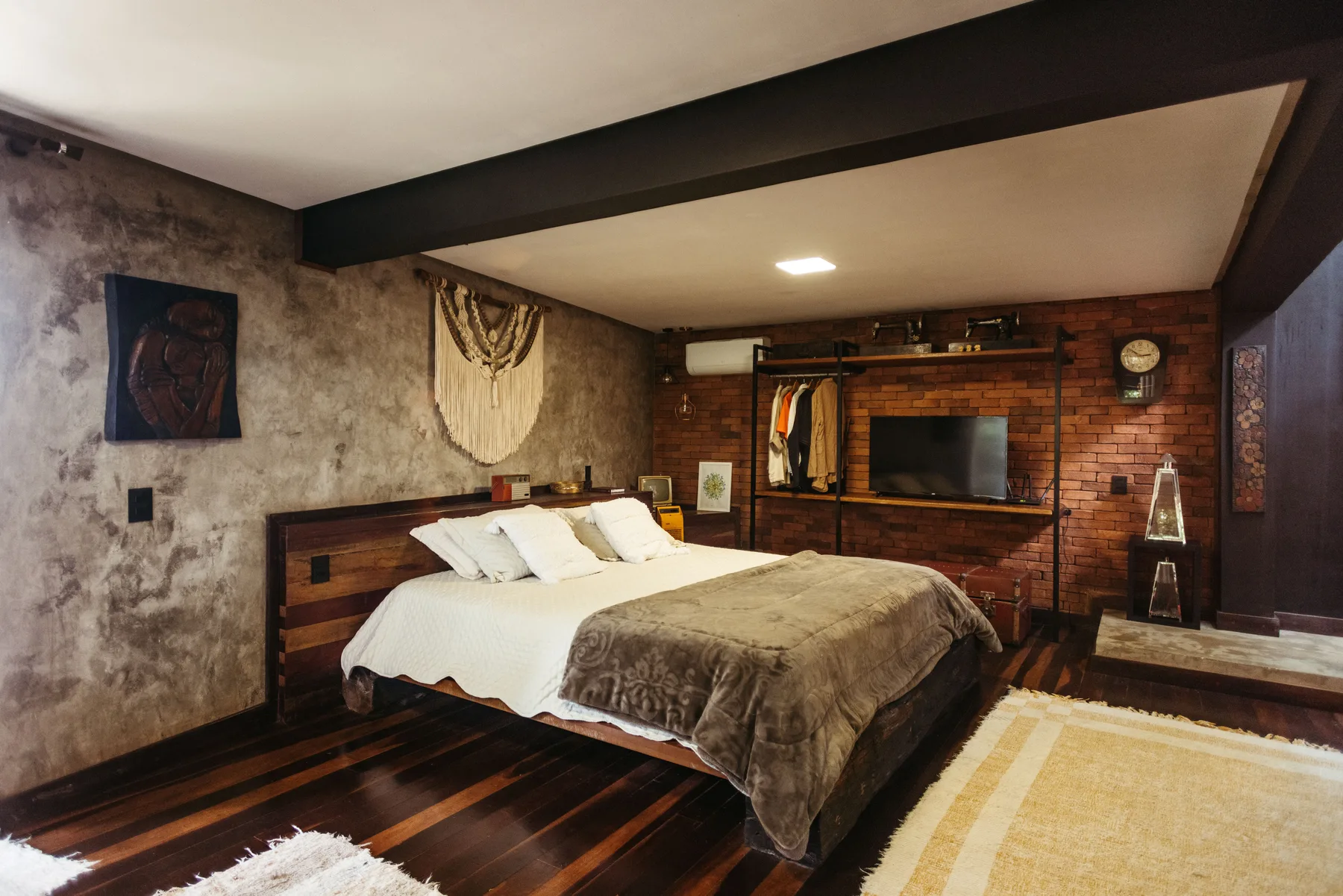 Guest room with a textured plaster wall, timber ceiling and layered bedding
