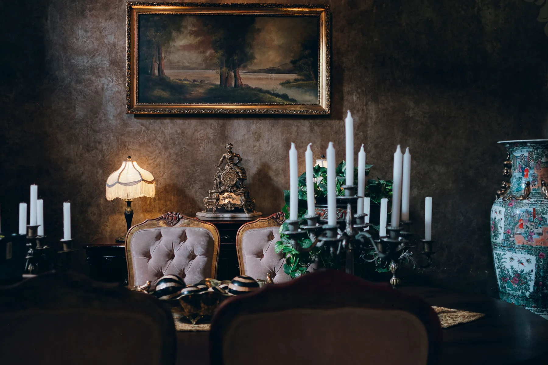 Dining room with warm limewashed walls, gilt framed painting and candlelight